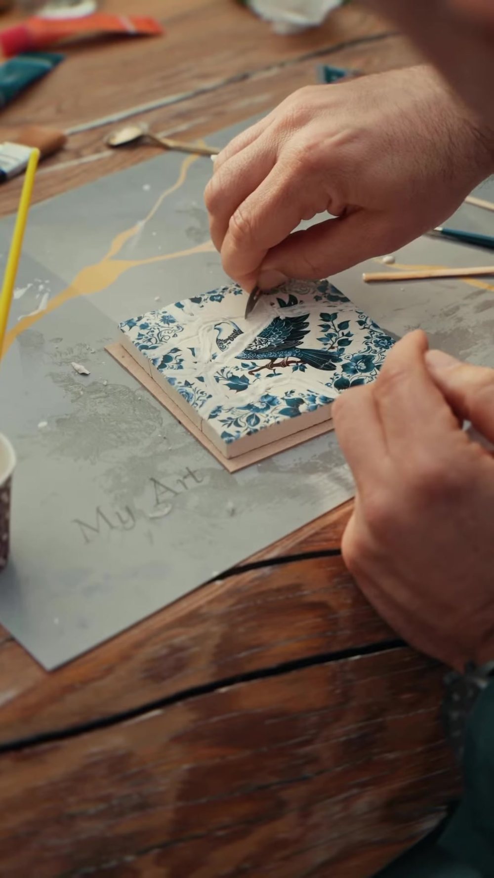 Tracing a crack in gold on a blue-and-white tile